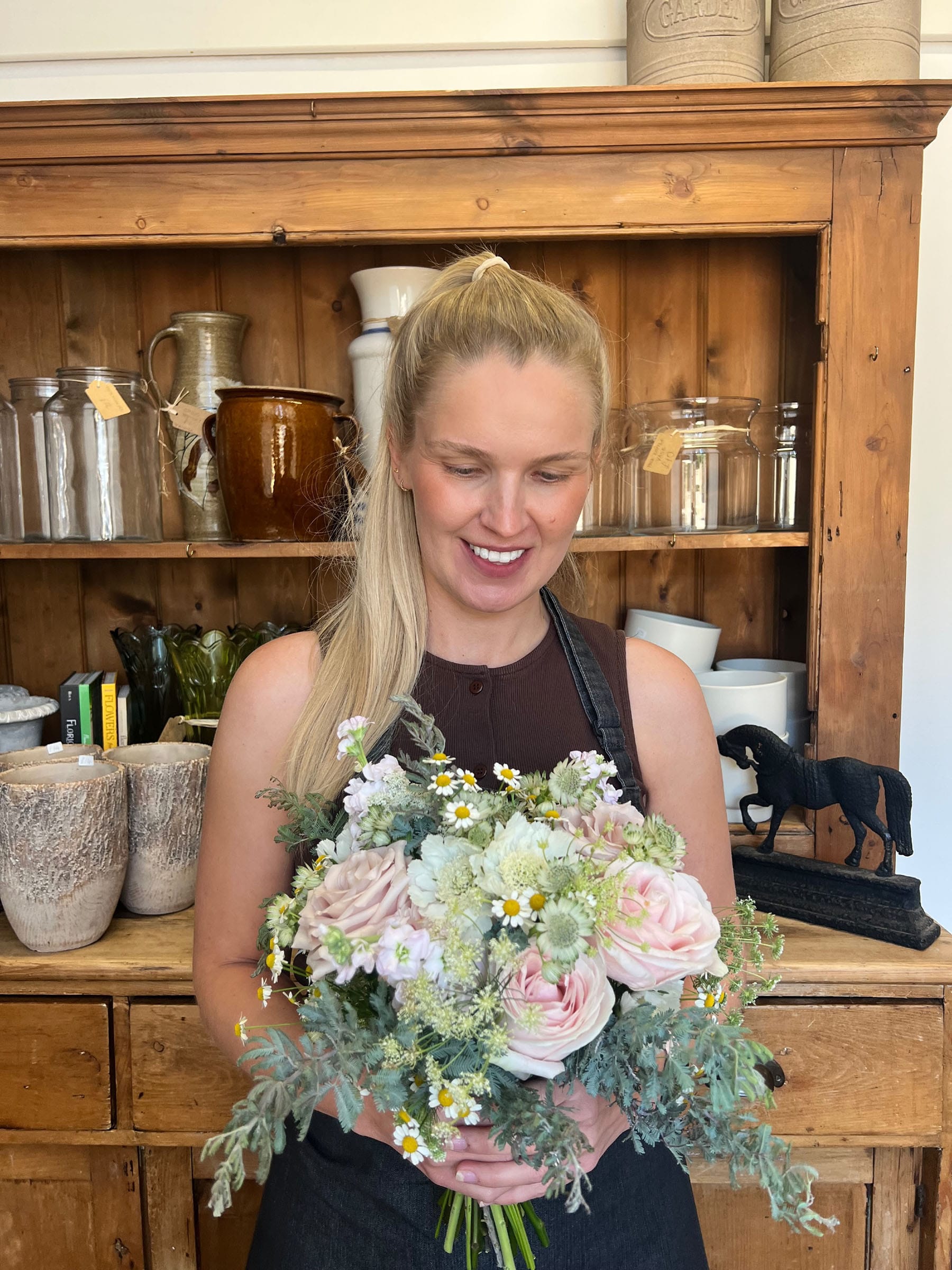 Smiling florist holding a bouquet in shop.