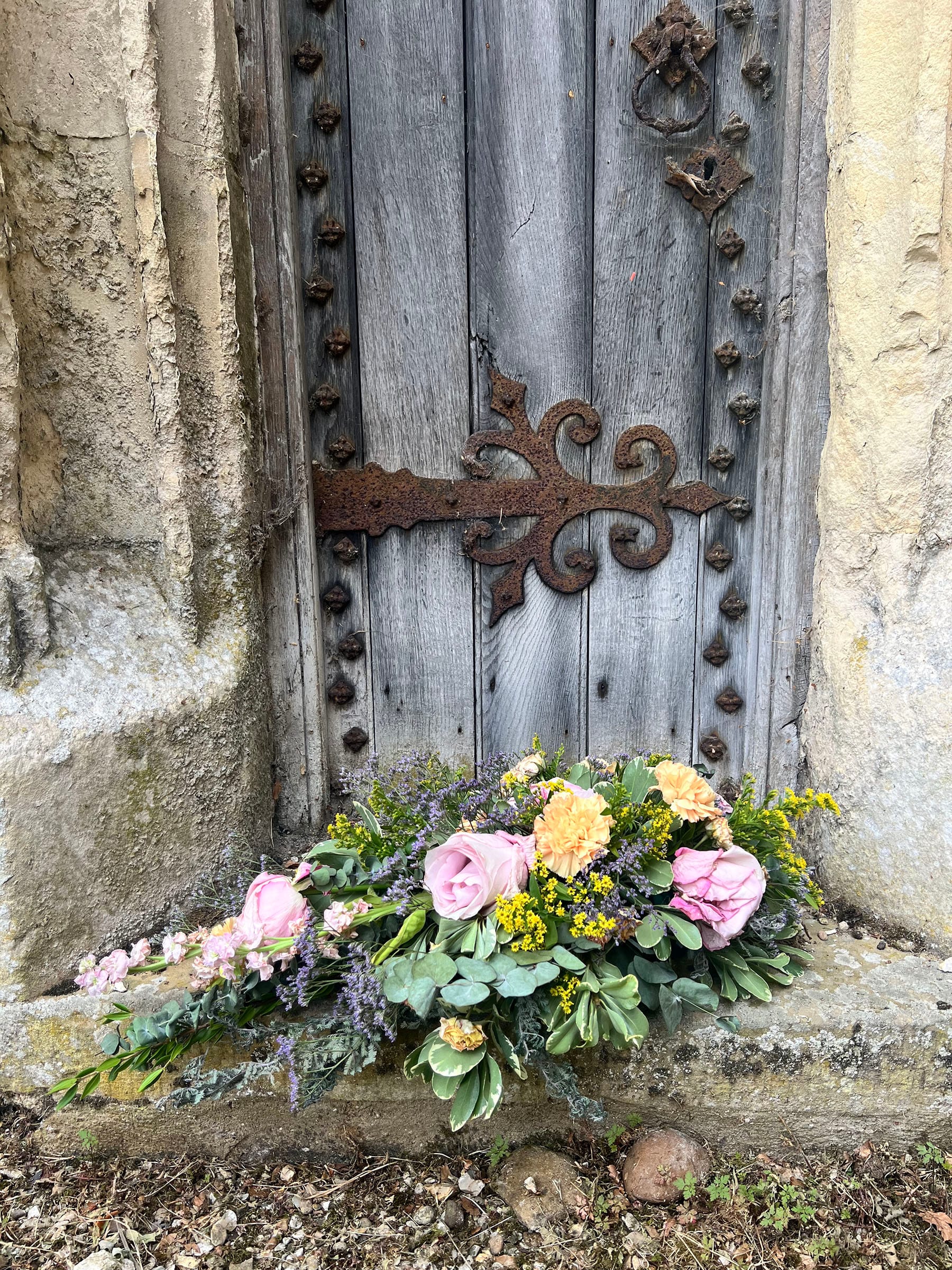 Rustic stone doorway with colourful flower arrangement.
