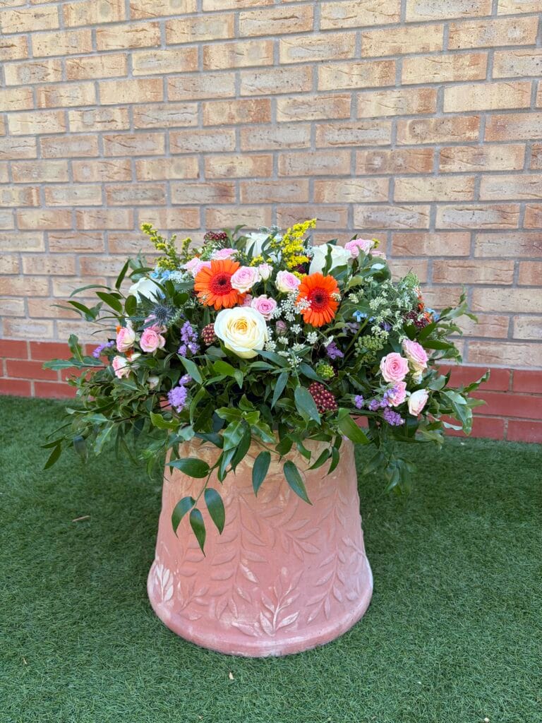 Round funeral posy arrangement with roses and gerberas