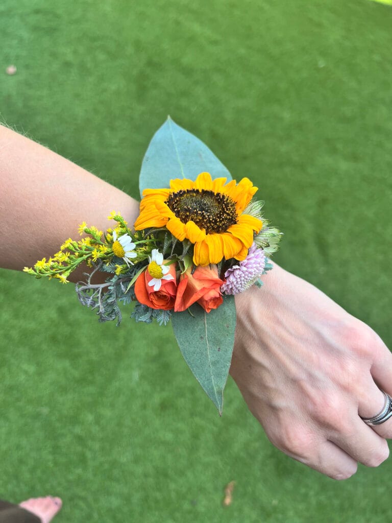 Floral bracelet with sunflowers and roses on wrist.