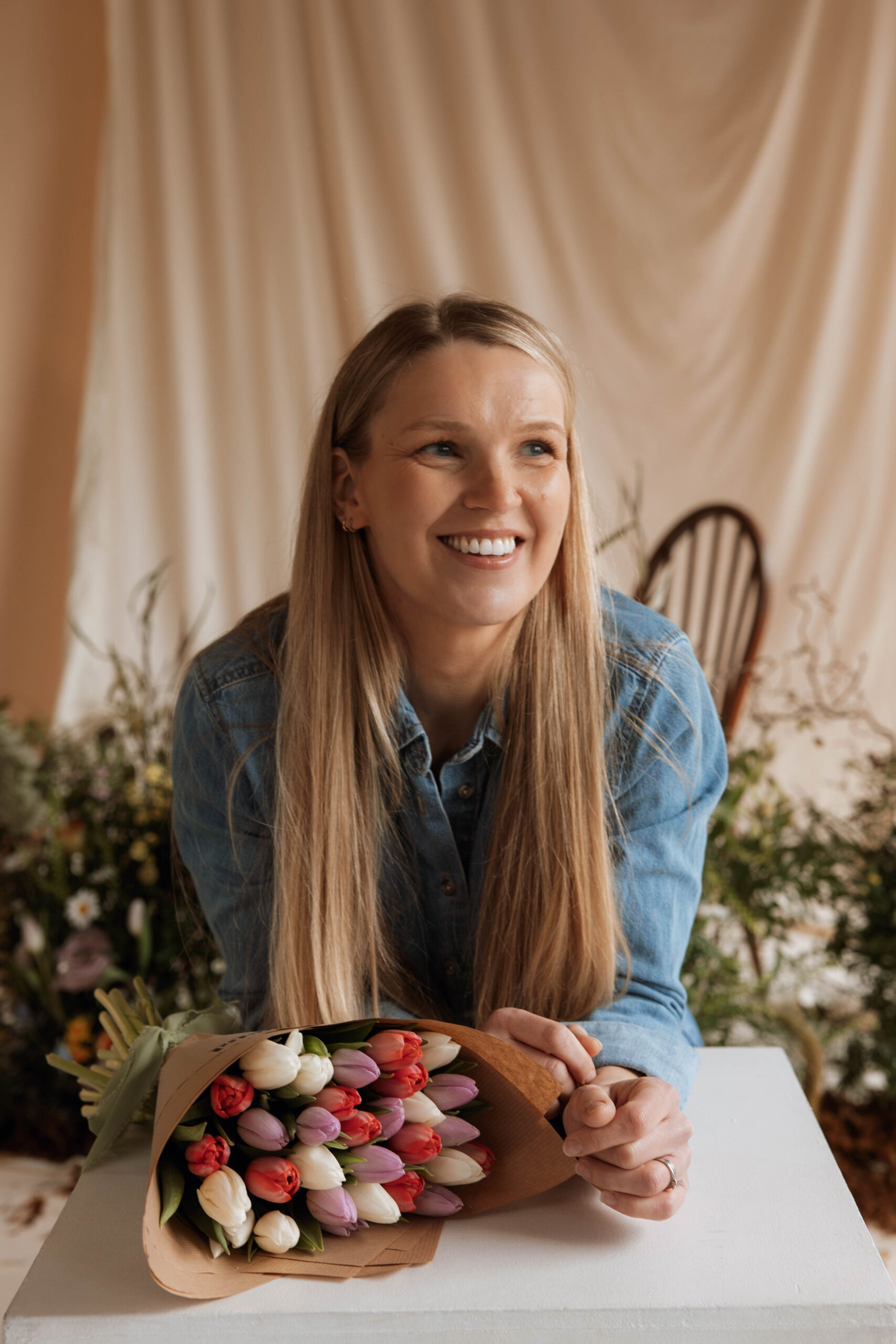 Smiling woman with tulip bouquet indoors.