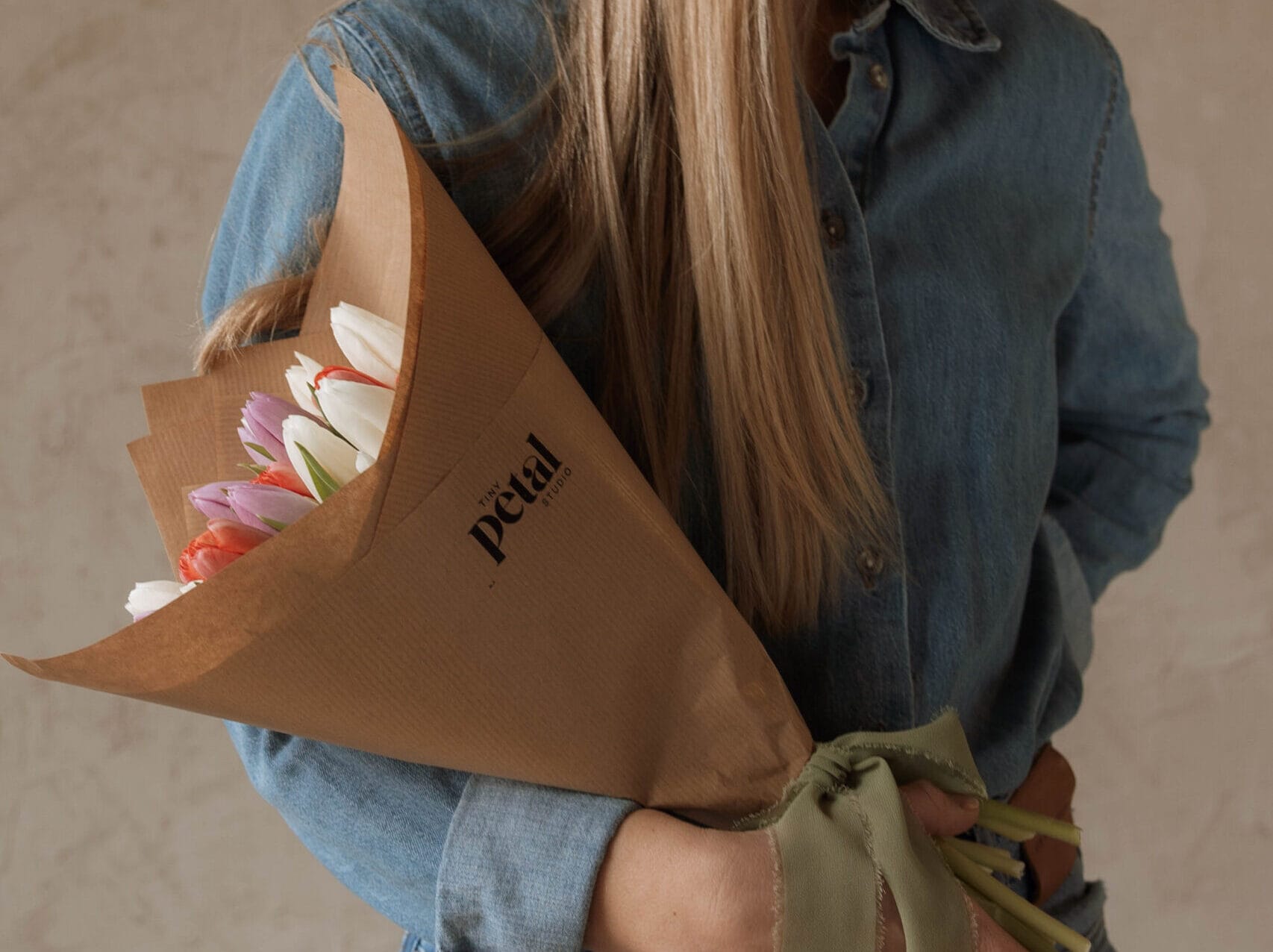Person holding bouquet of tulips in denim outfit.