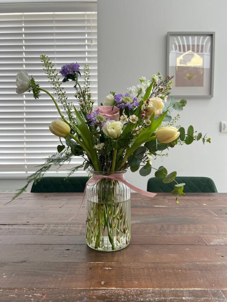 Colourful bouquet in glass vase on wooden table.