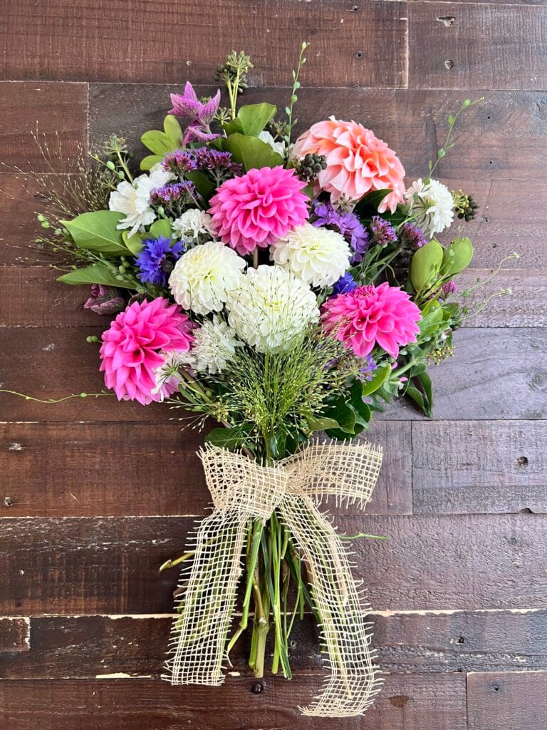 Colourful floral bouquet with ribbon on wooden table.